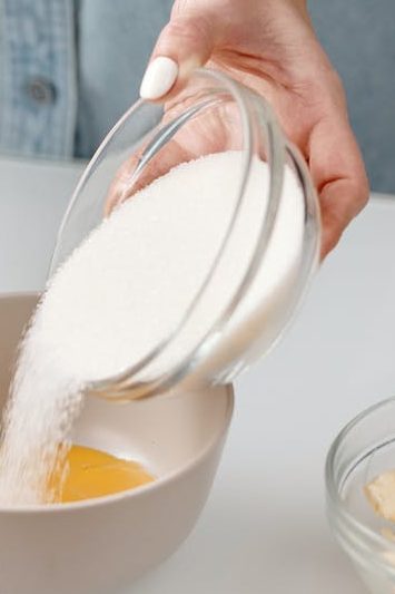 person pouring powdered sugar in a bowl